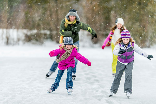 Familie beim Schlittschuhfahren - Weihnachten im Schnee