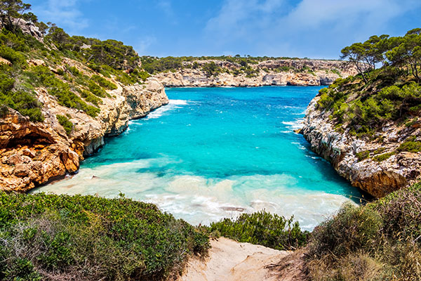 Azurblaues Wasser umrahmt von Felsen an der Cala Morro