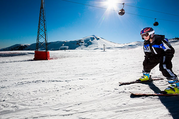 Junge auf der Piste vor Skilift