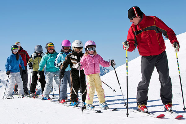 Skileher mit Kindern beim Skifahren